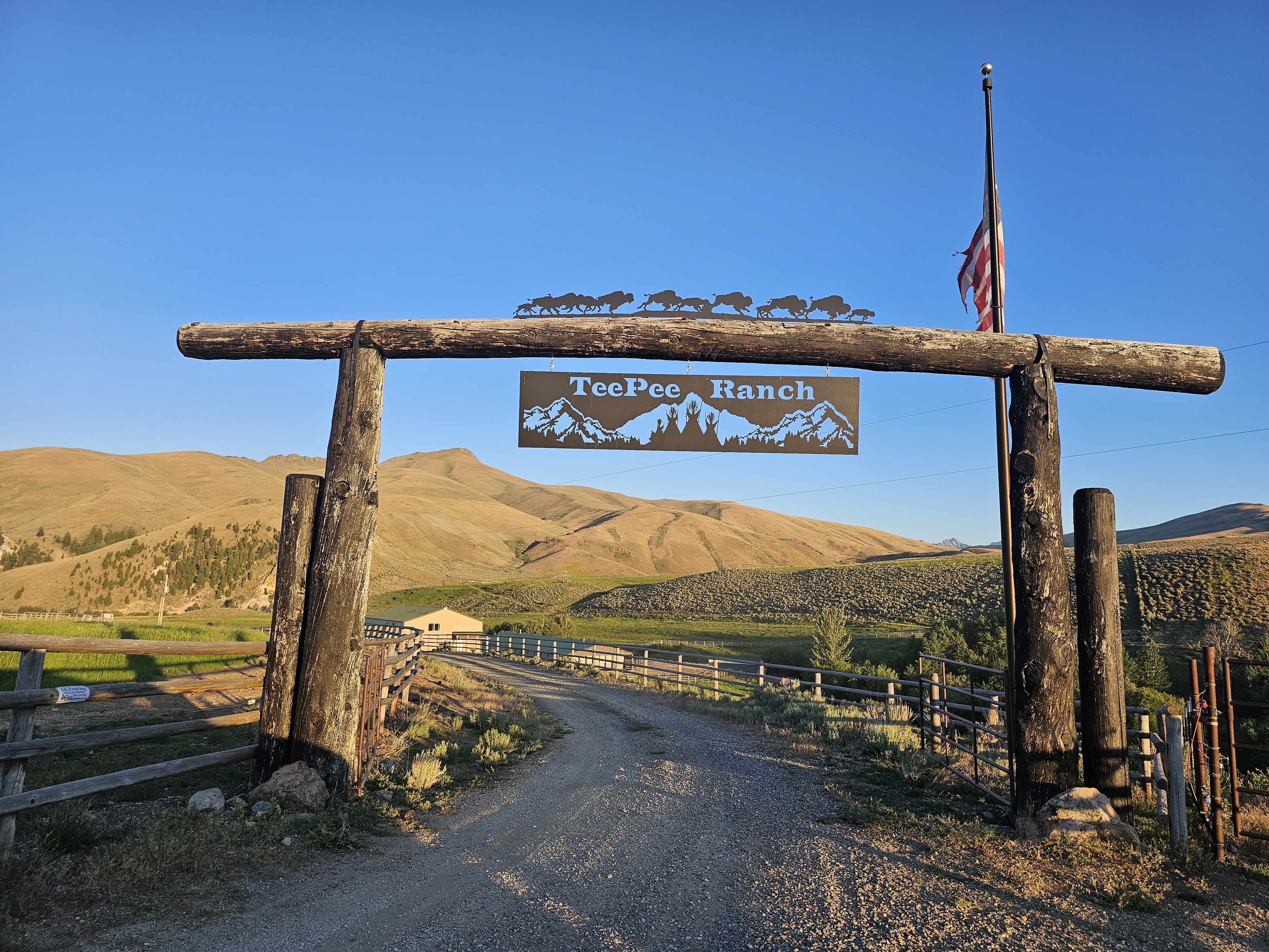 Custom metal sign 'TeePee Ranch' with mountain and buffalo silhouettes, hanging from a grand wooden entrance.