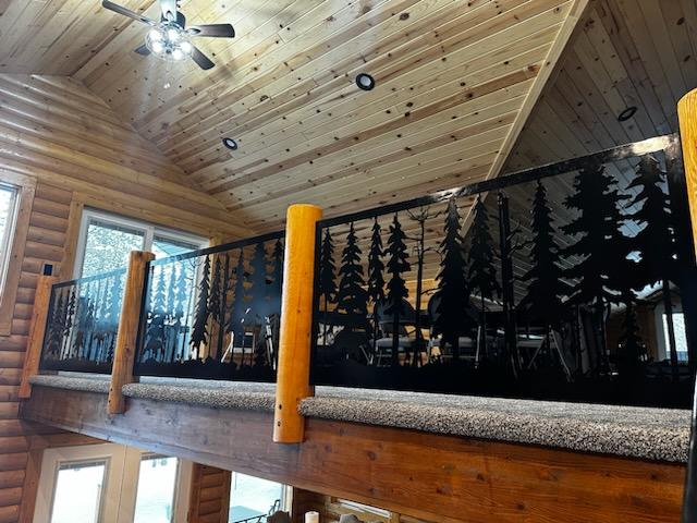 Custom metal railing system featuring continuous pine forest silhouettes along both a loft and staircase in a log cabin style home.