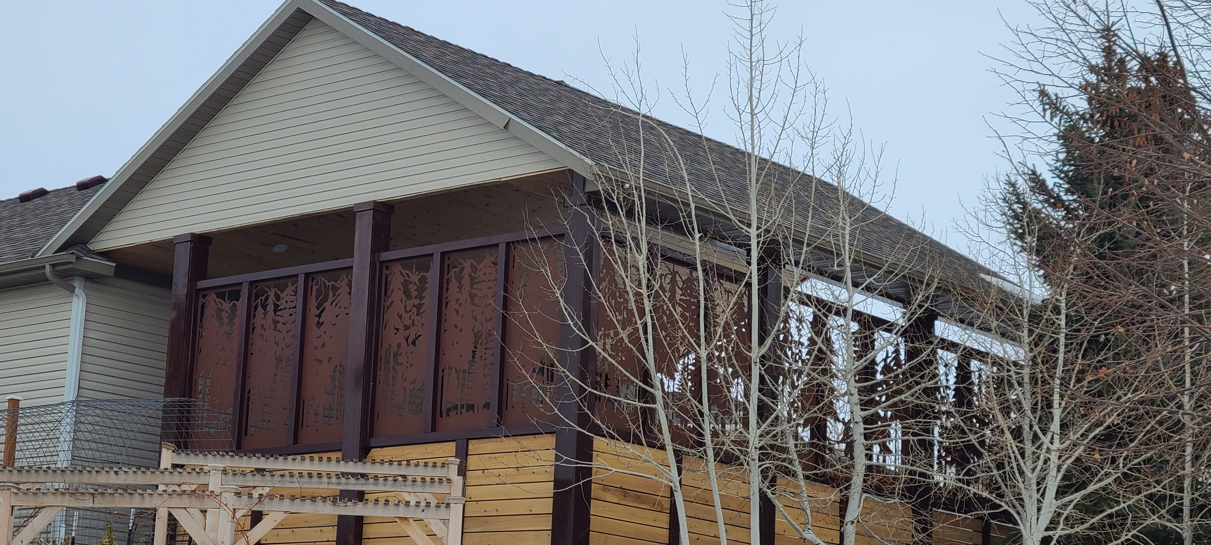 Custom metal deck railing and privacy screen with an aspen tree design and a rust patina finish.